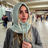 Person wearing a mint knitted hood in an indoor setting