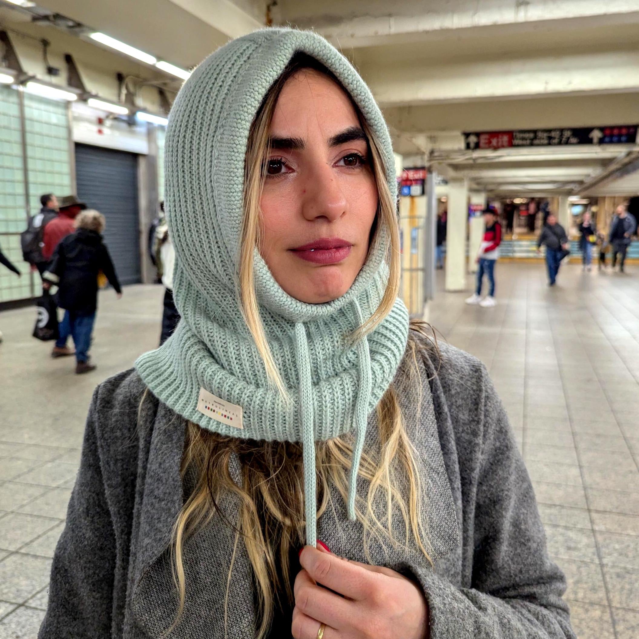 Person wearing a mint knitted hood in an indoor setting