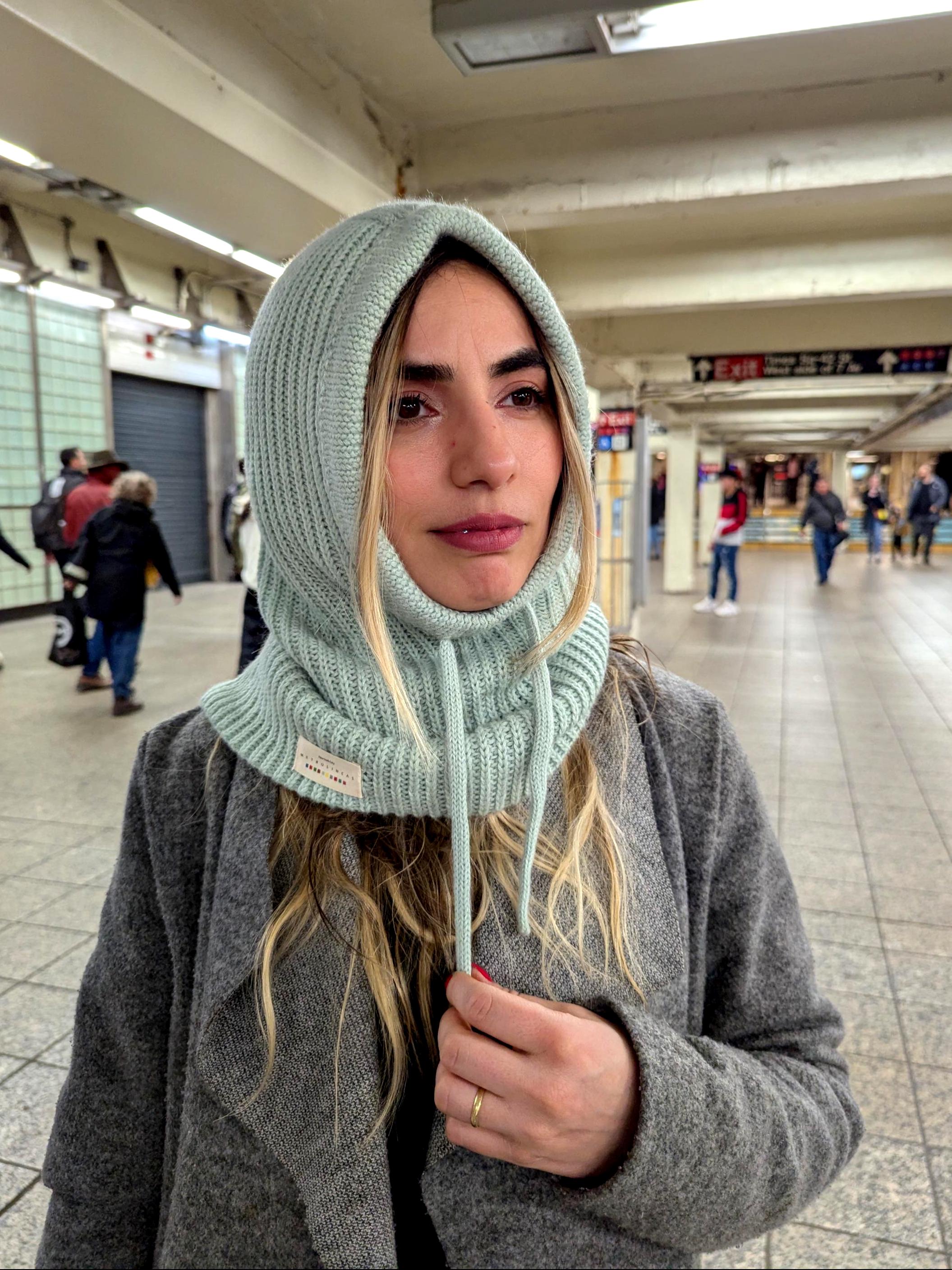 Person wearing a mint knitted hood in an indoor setting