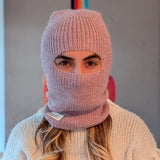 Person wearing a pink knitted balaclava with a blurred background