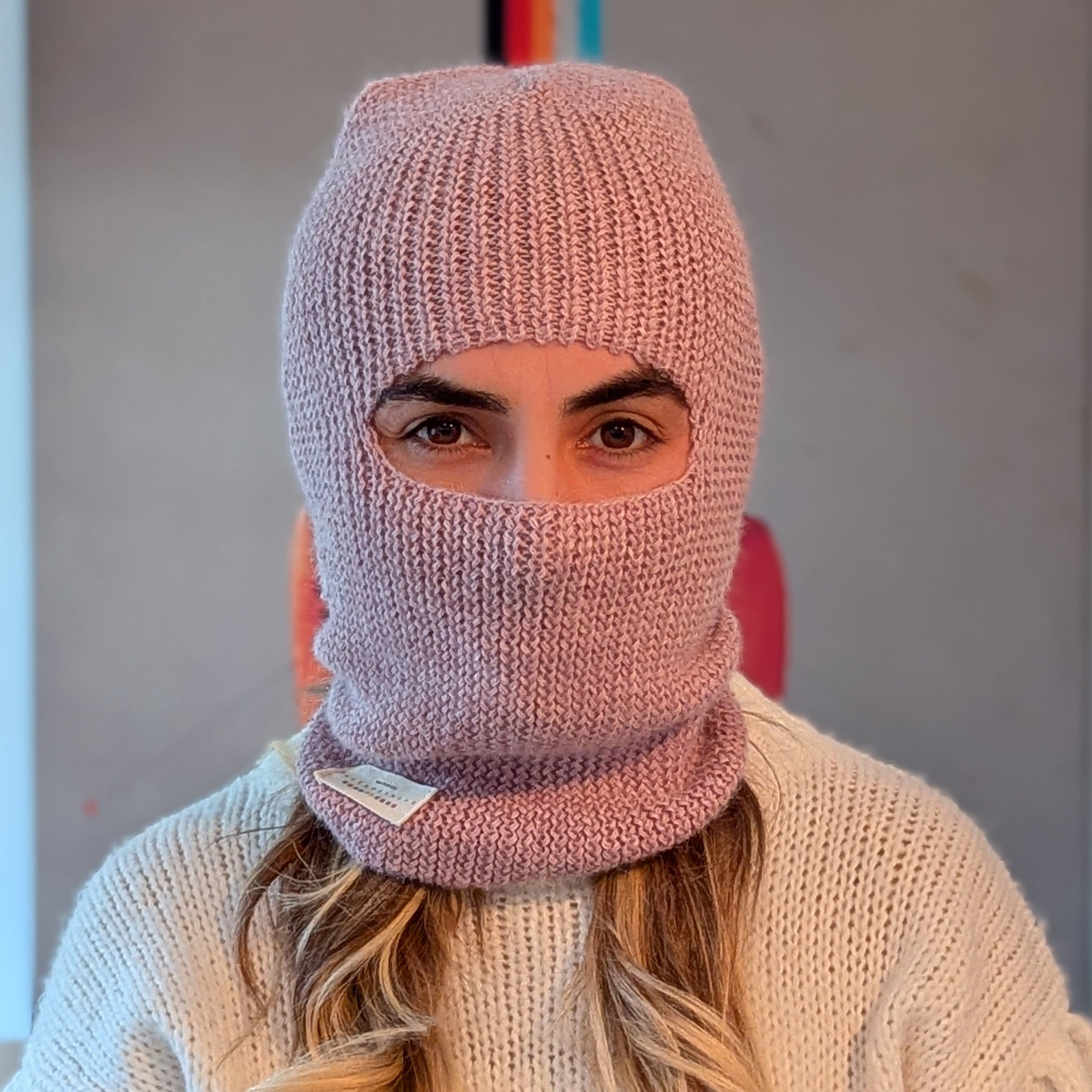 Person wearing a pink knitted balaclava with a blurred background