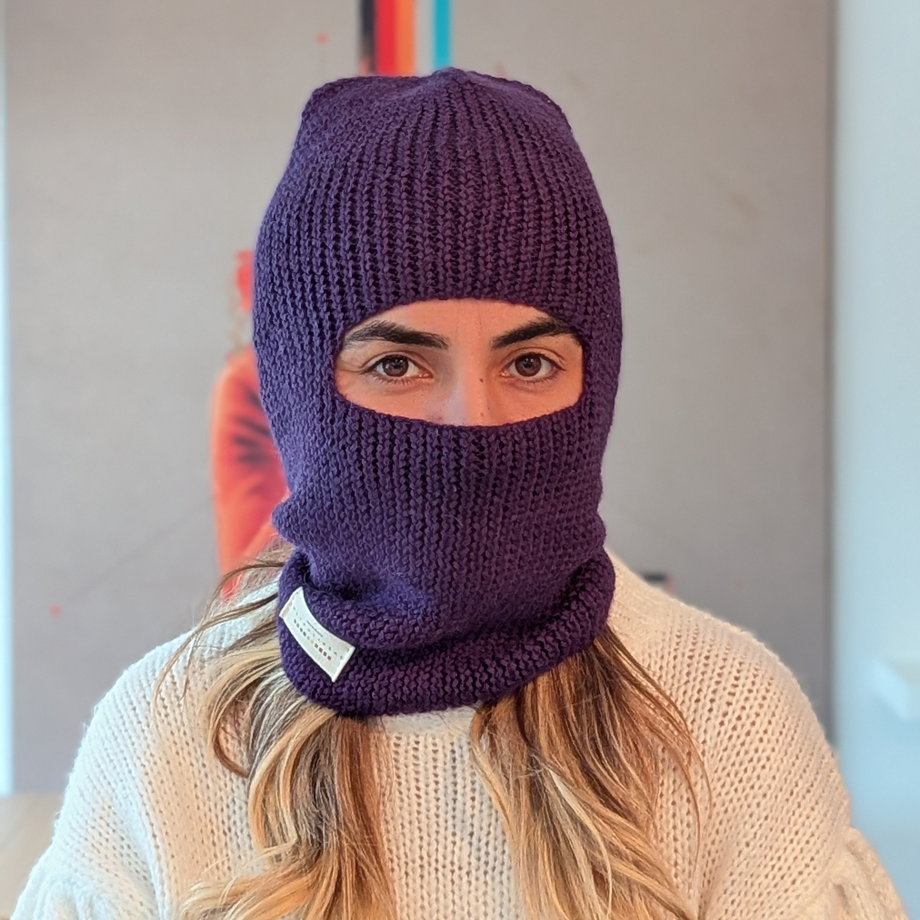 Person wearing a purple knitted balaclava indoors