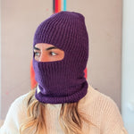 Person wearing a purple knitted balaclava against a neutral background