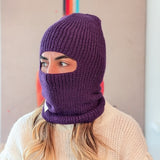 Person wearing a purple knitted balaclava against a neutral background