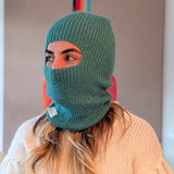 Person wearing a green knitted balaclava with a blurred background