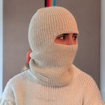 Person wearing a white knitted balaclava against a neutral background