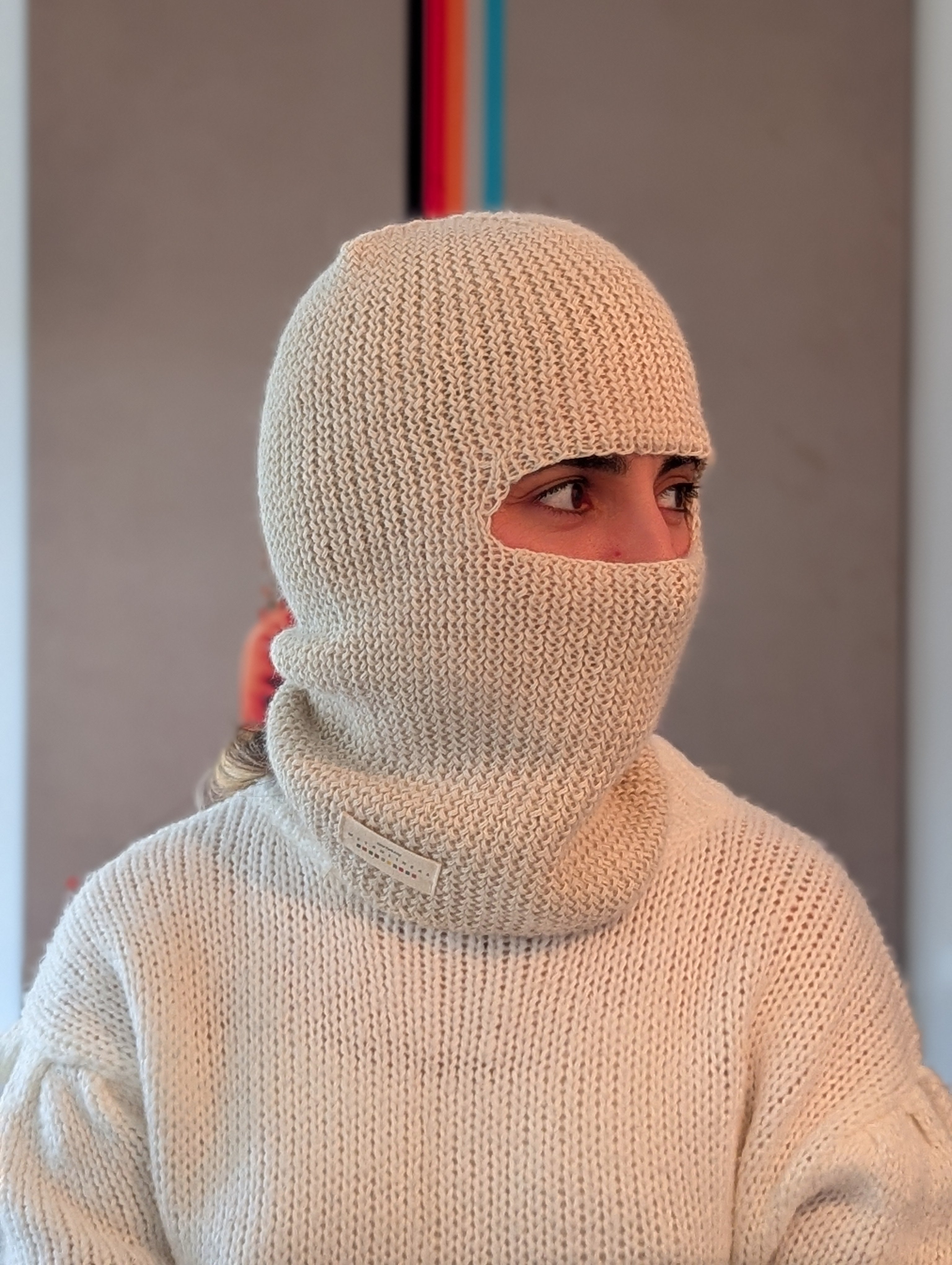 Person wearing a white knitted balaclava against a neutral background