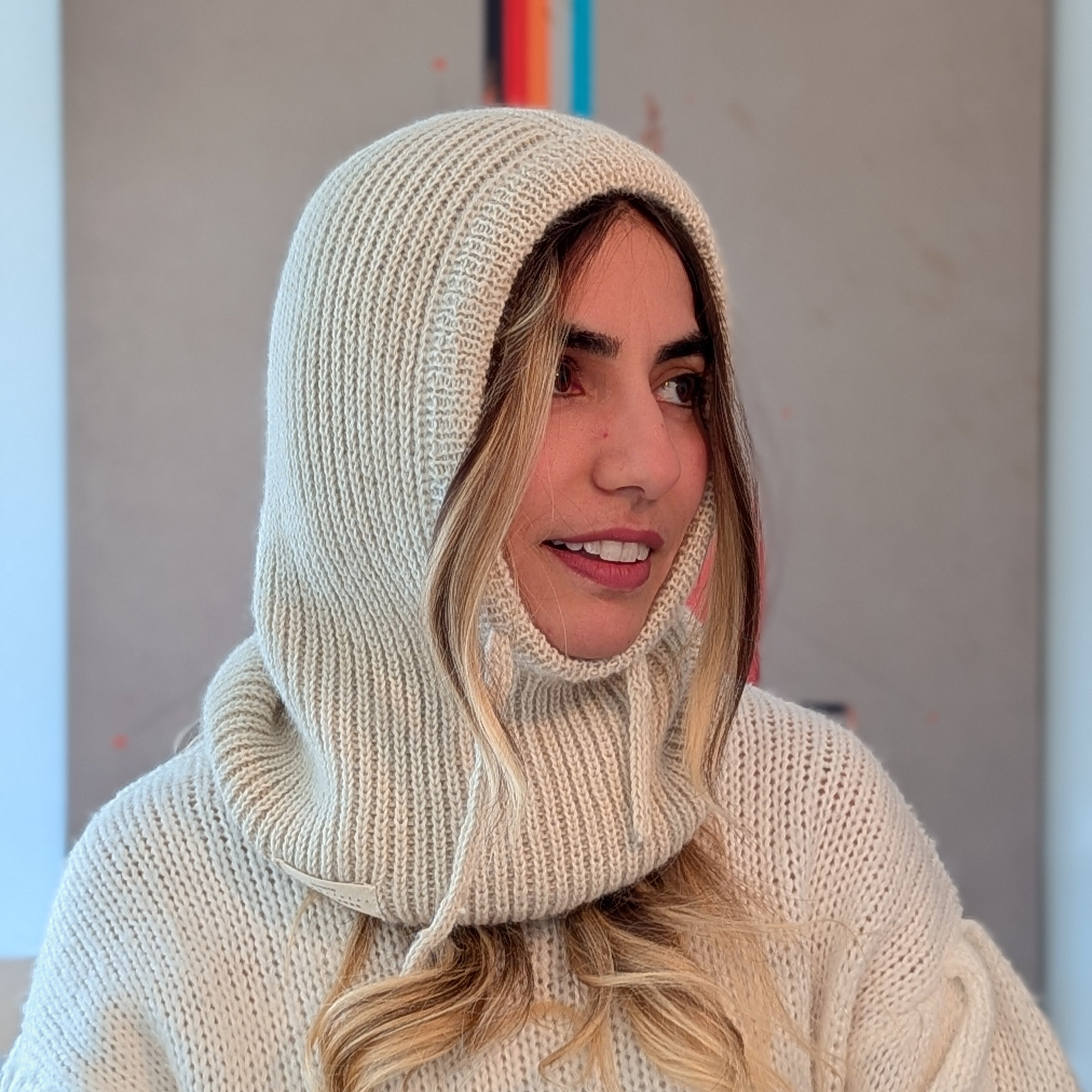 Woman wearing a white knit hooded sweater with a blurred background