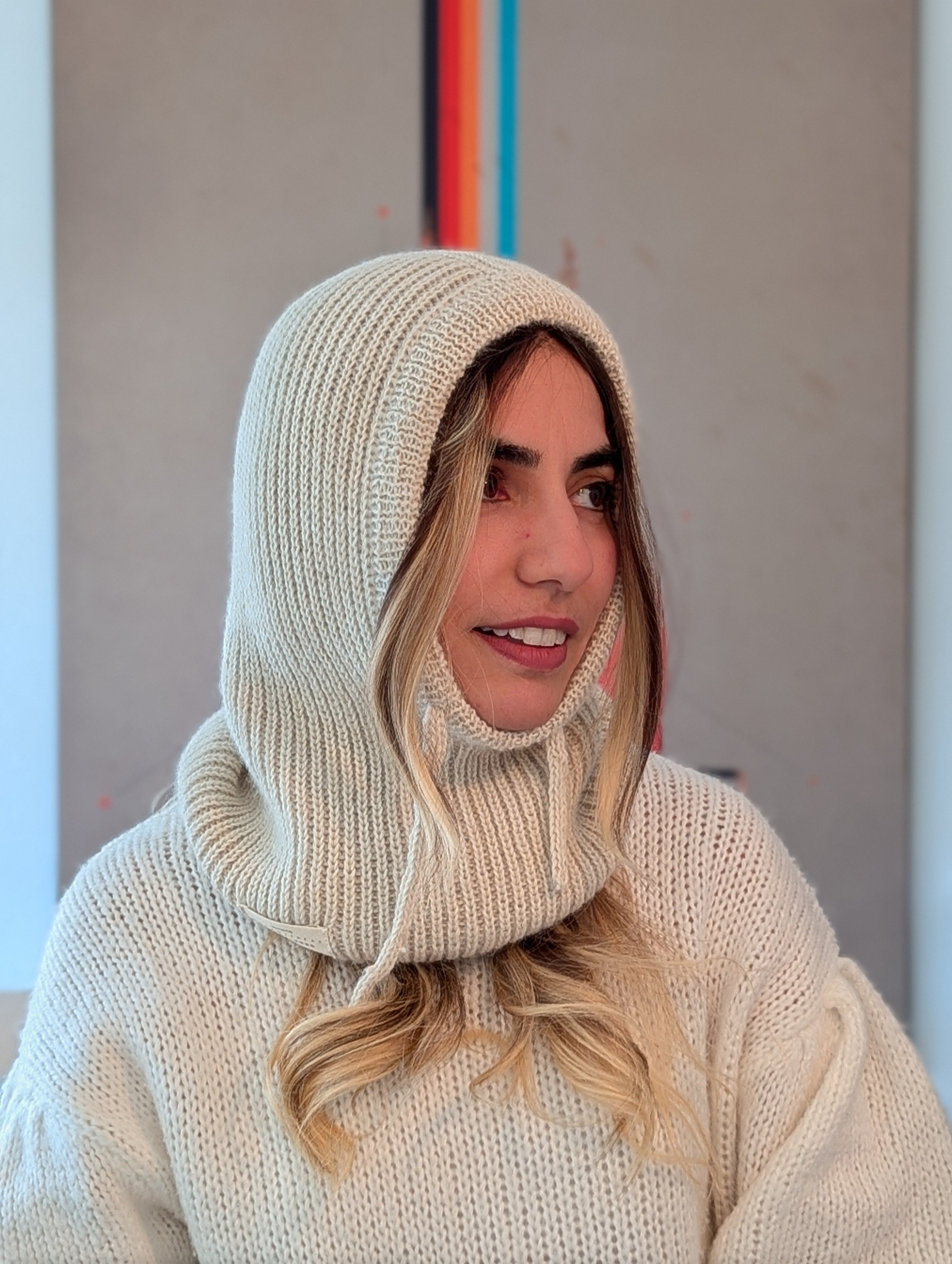 Woman wearing a white knit hooded sweater with a blurred background