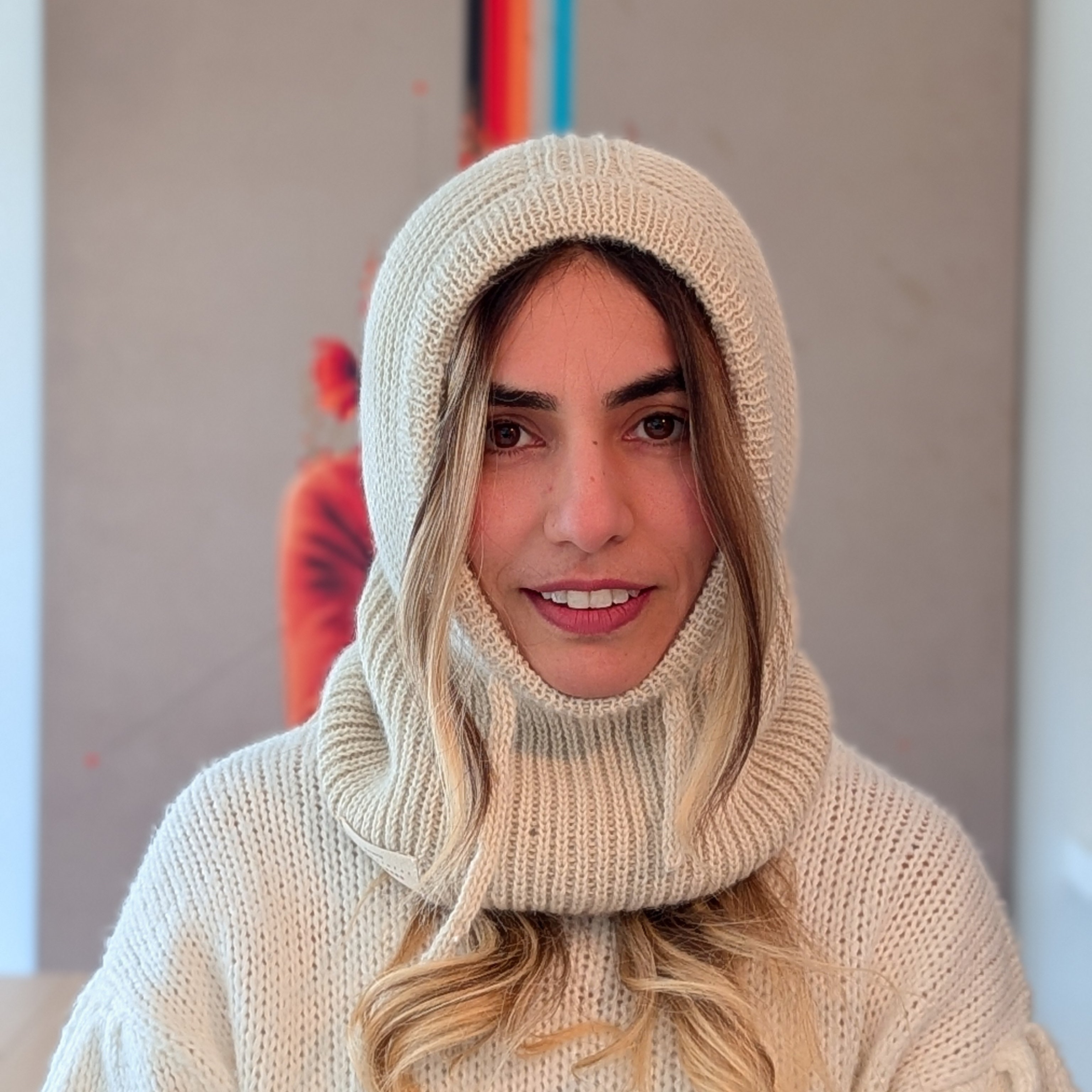 Person wearing a white knit sweater and hood indoors