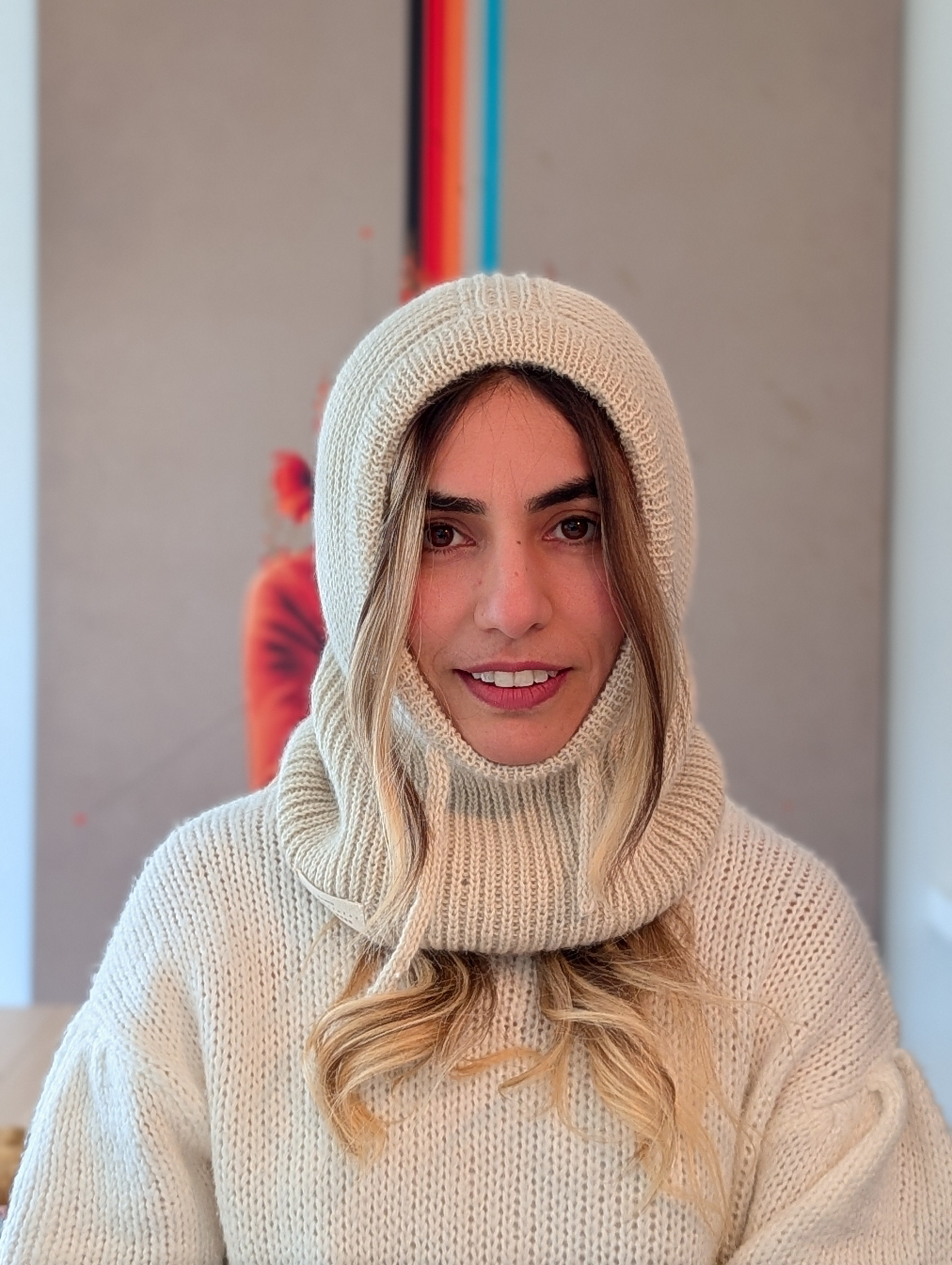 Person wearing a white knit sweater and hood indoors