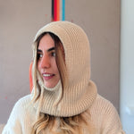 Person wearing a white knitted hood and sweater in an indoor setting