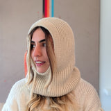 Person wearing a white knitted hood and sweater in an indoor setting