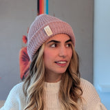 Woman wearing a pink beanie and light sweater against a neutral background