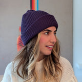 Woman wearing a purple beanie and light sweater against a neutral background
