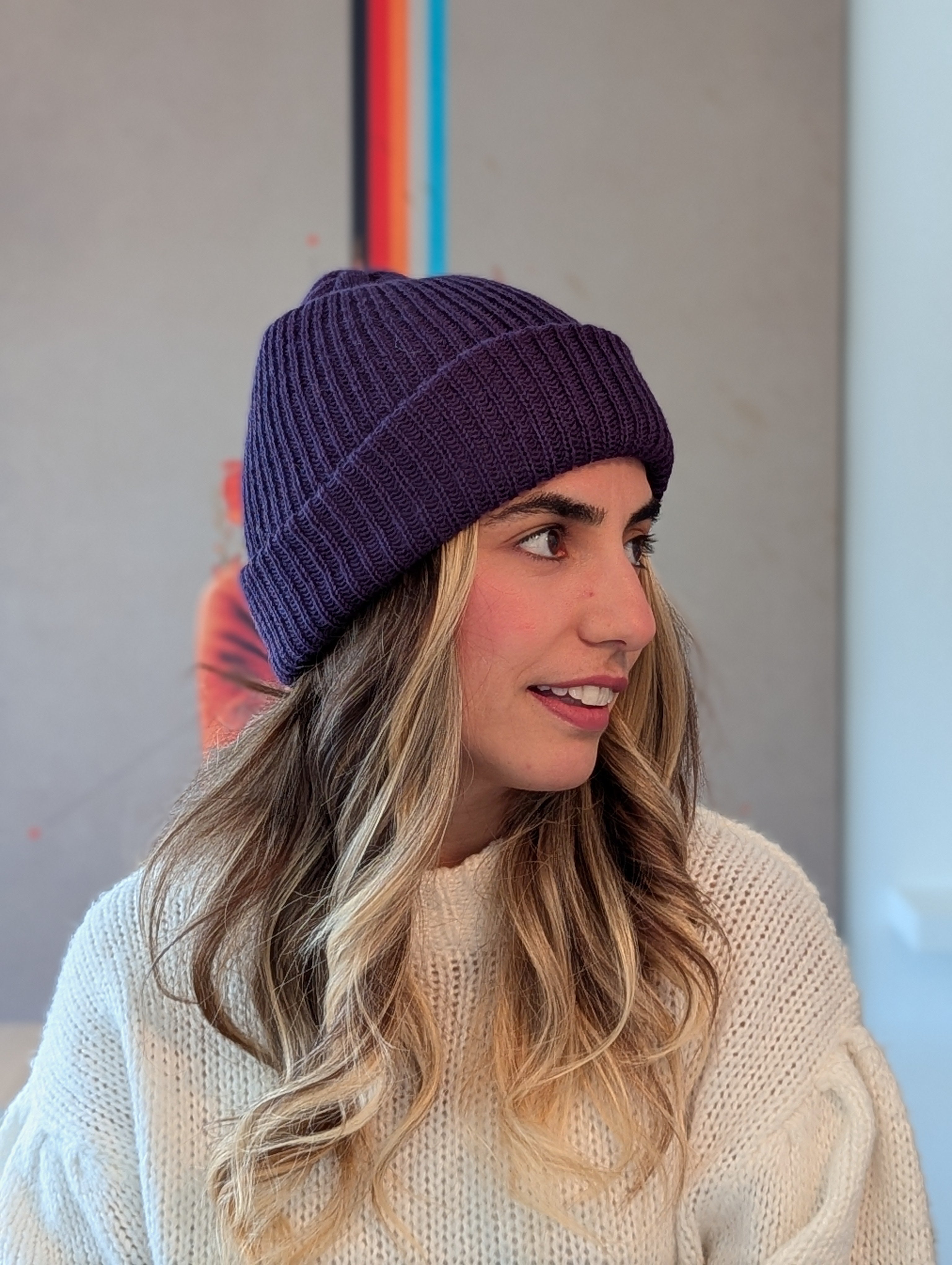 Woman wearing a purple beanie and light sweater against a neutral background