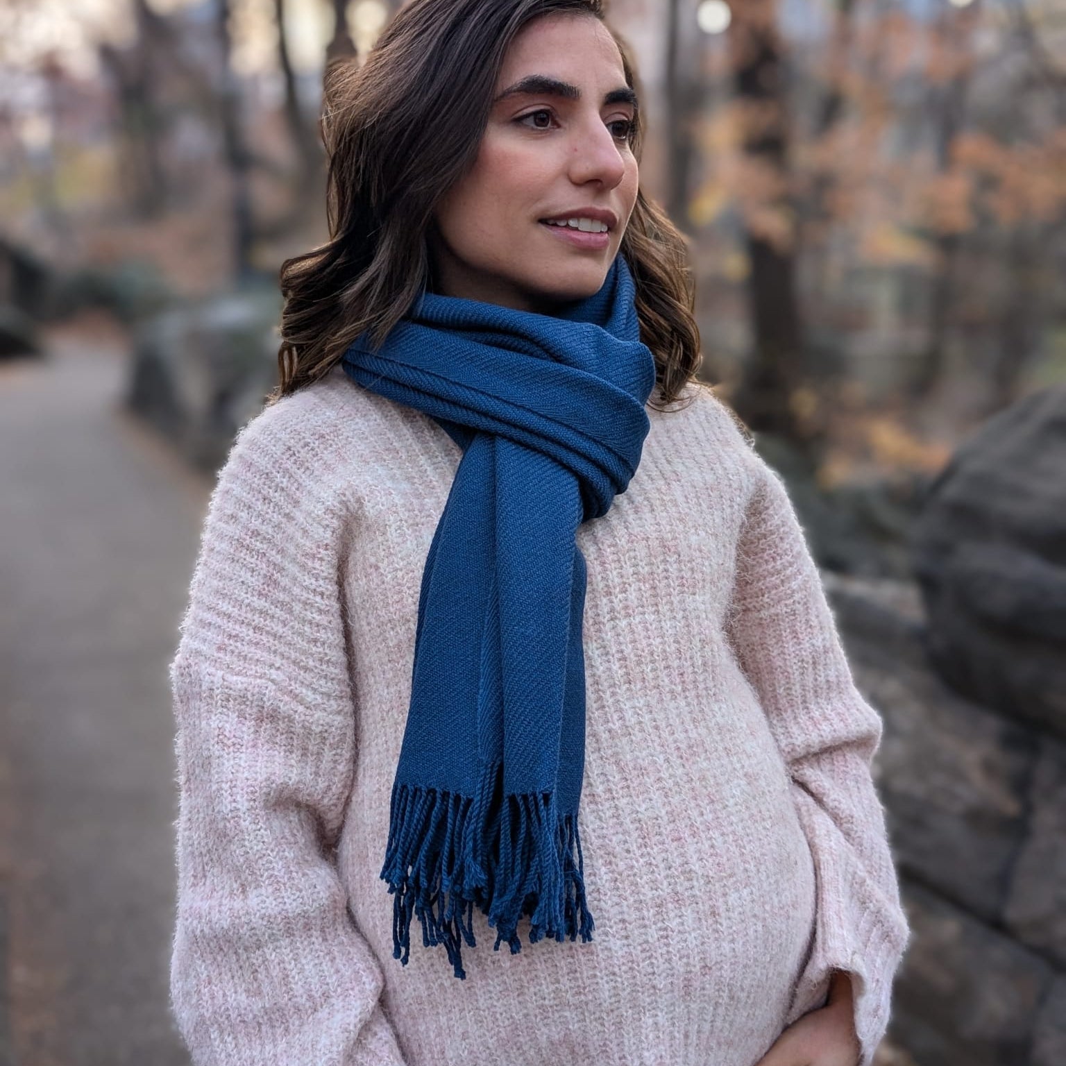 Woman wearing a blue scarf standing outdoors with trees in the background