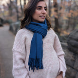 Woman wearing a blue scarf standing outdoors with trees in the background