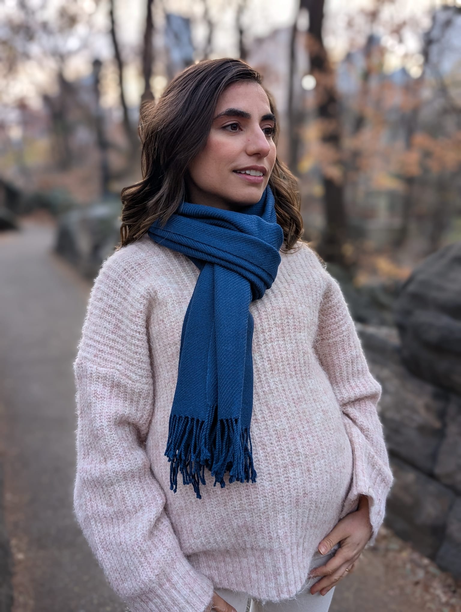 Woman wearing a blue scarf standing outdoors with trees in the background