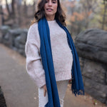 Woman wearing a blue scarf standing outdoors with a natural background
