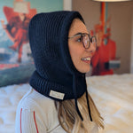 Woman wearing a black knitted hood in a room with colorful decor