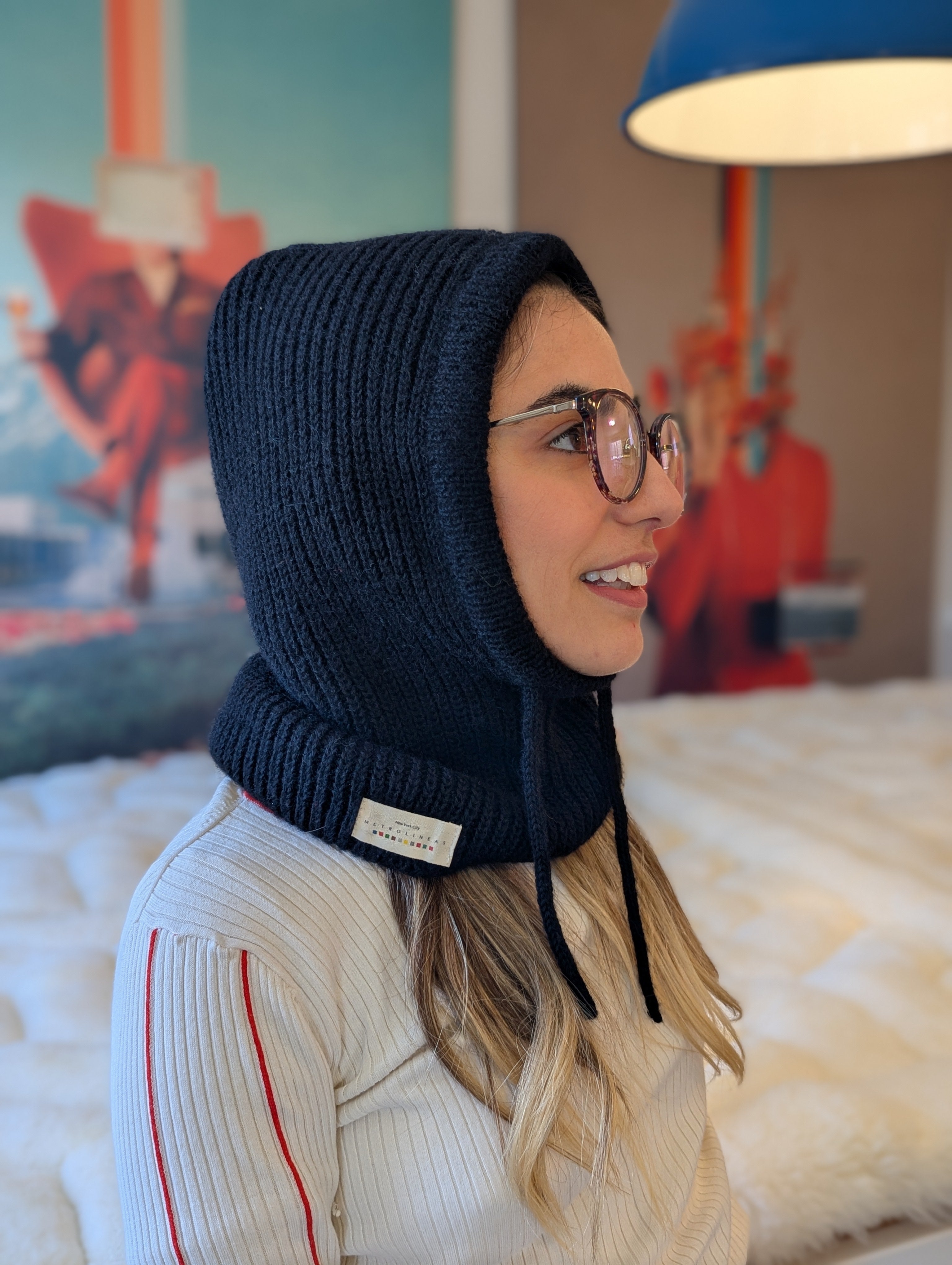 Woman wearing a black knitted hood in a room with colorful decor