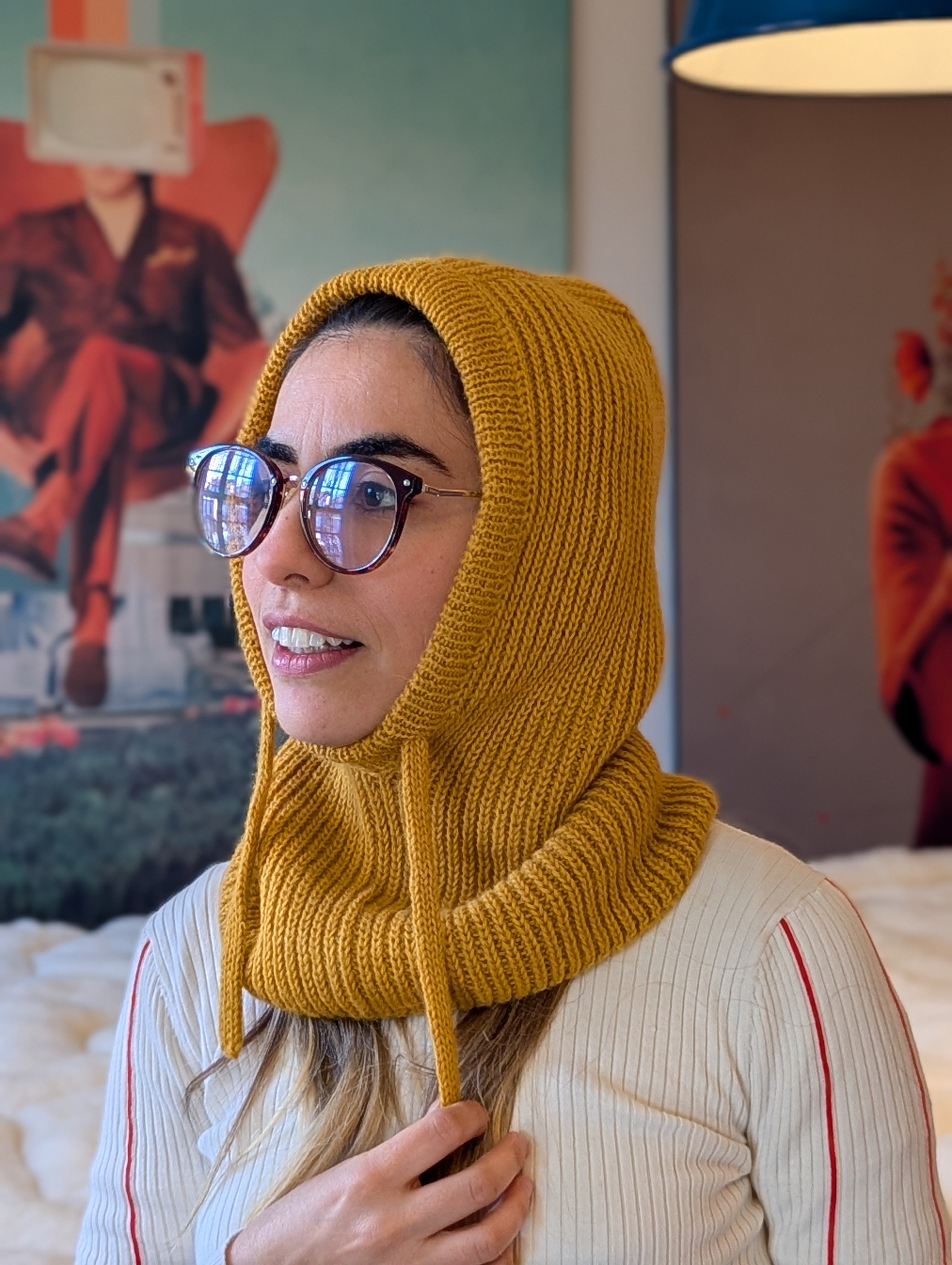 Woman wearing a mustard yellow knitted hood in an indoor setting